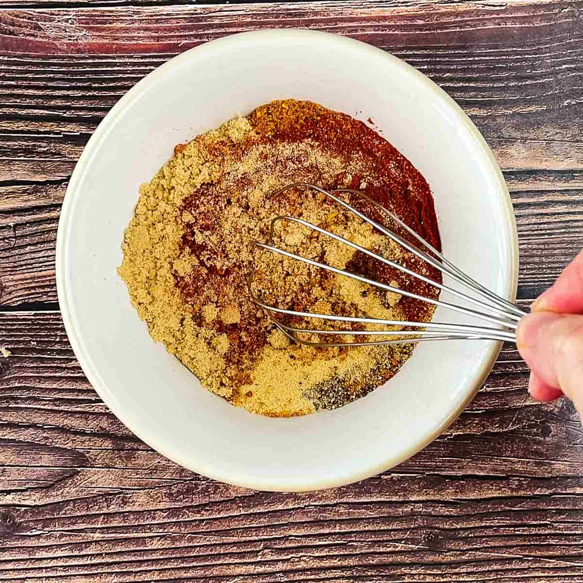 Whisking the ingredients for the dry run in a white bowl.