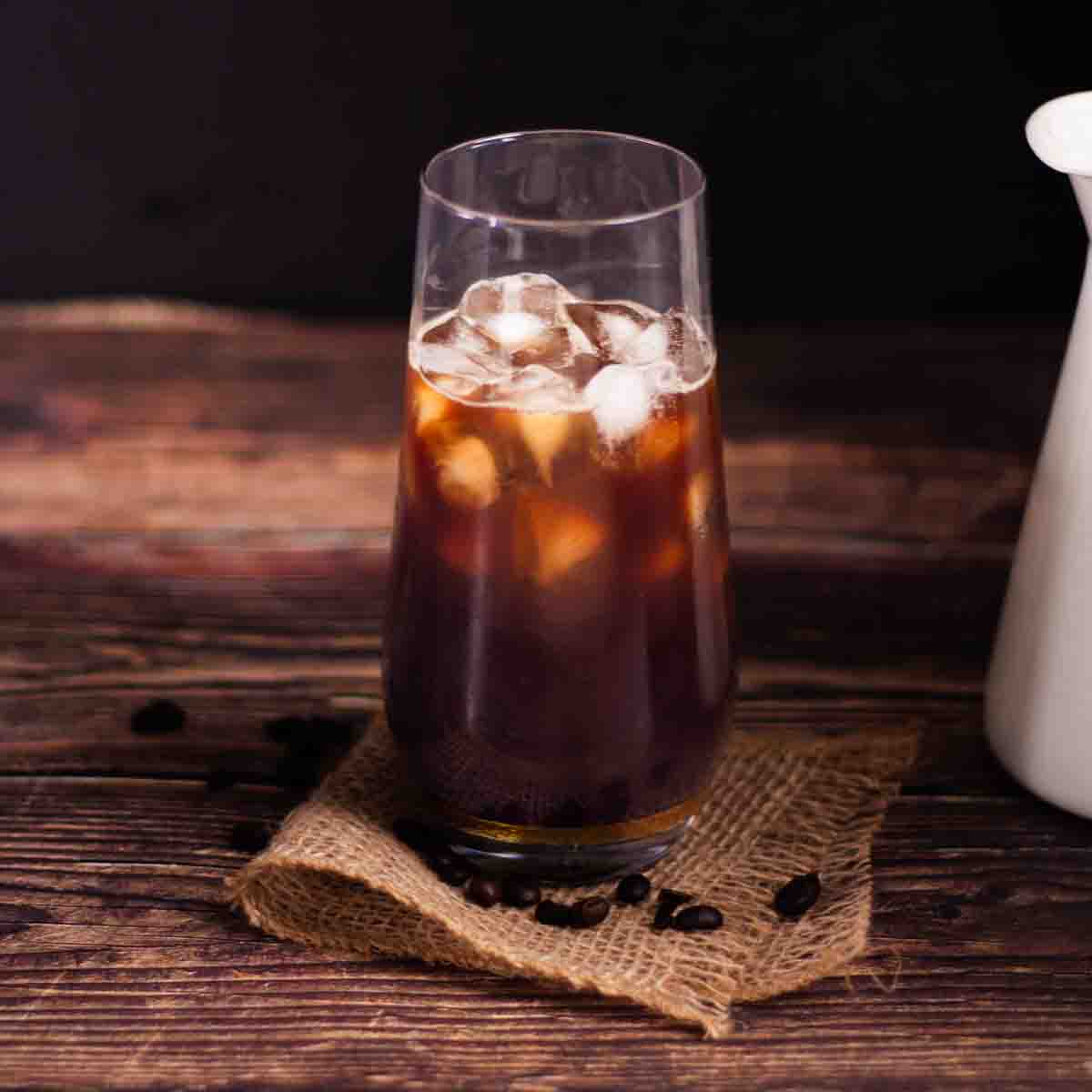 A tall glass filled with ice cubes and cooled coffee.