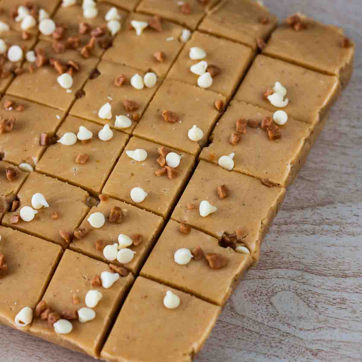 Neatly cut squares of pumpkin pie fudge on a wooden board.