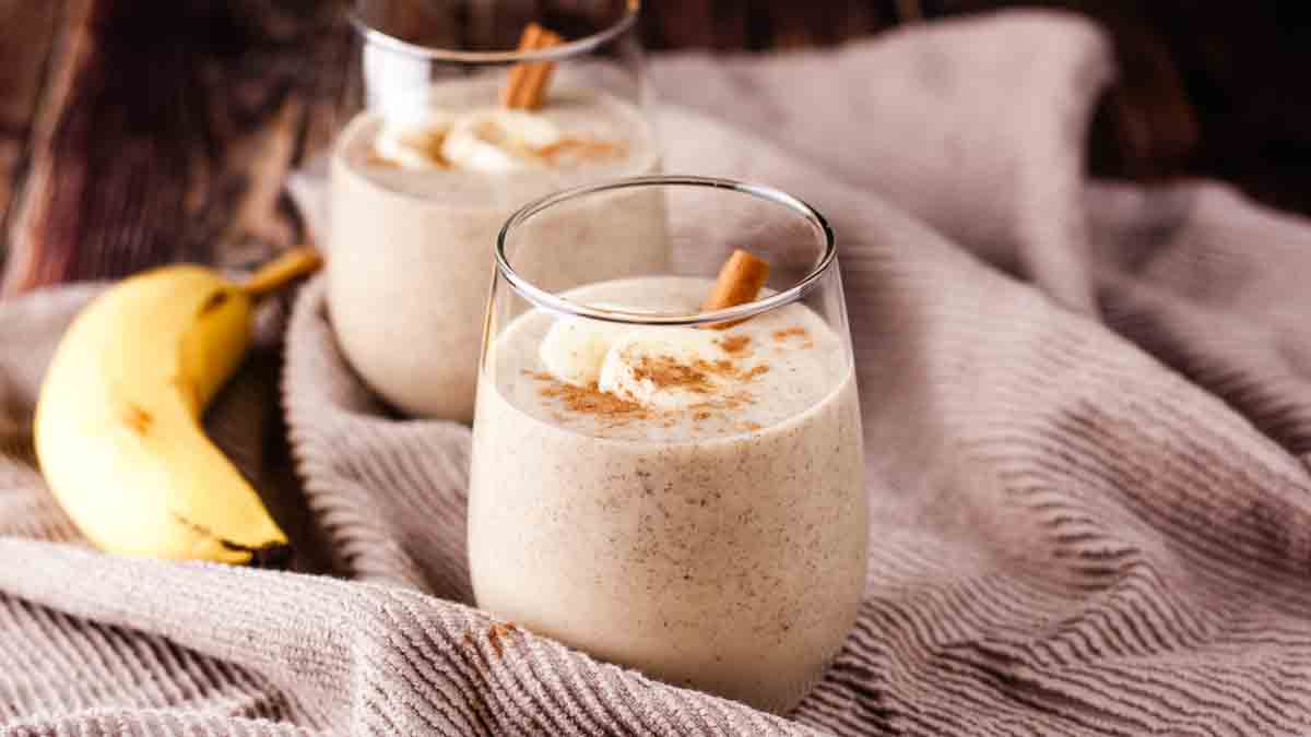 Banana smoothie in a short glass, garnished with fresh banana.