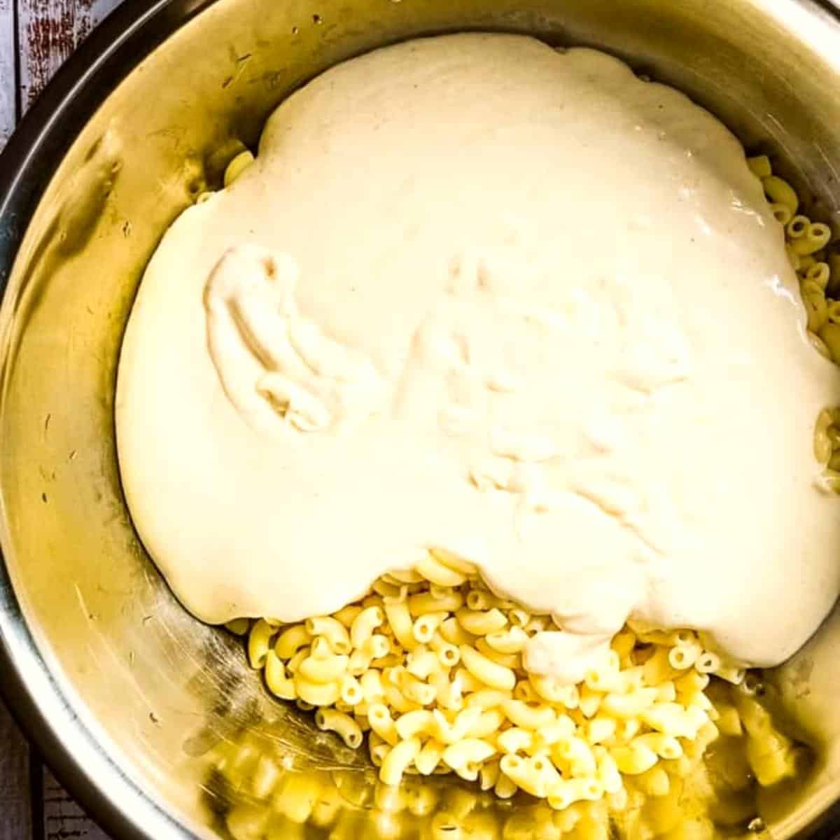 The creamy cheese sauce poured over the cooked macaroni in a large bowl.