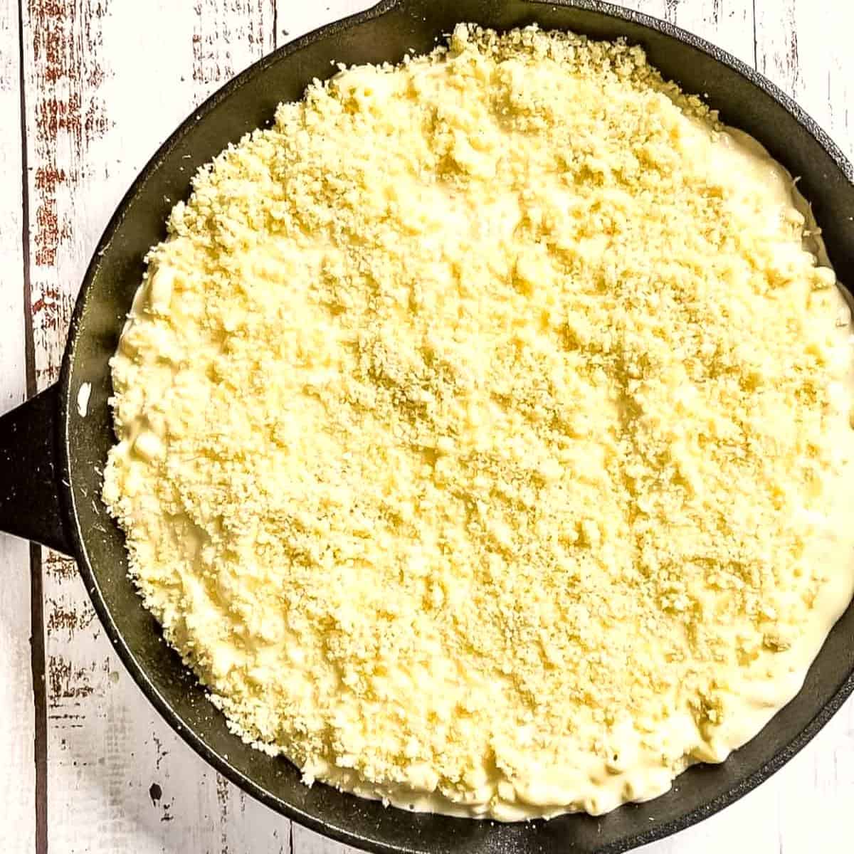 The Panko topping evenly spread on top of the cheese macaroni in the cast iron pan.