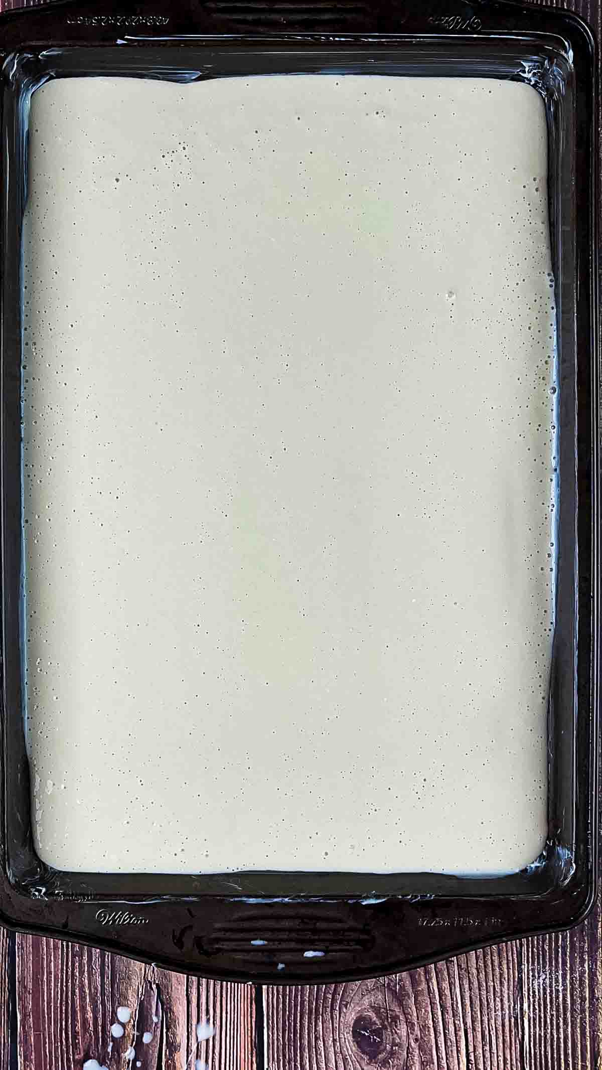 The pancake batter for the sheet pan pancakes poured onto a greased cookie sheet.
