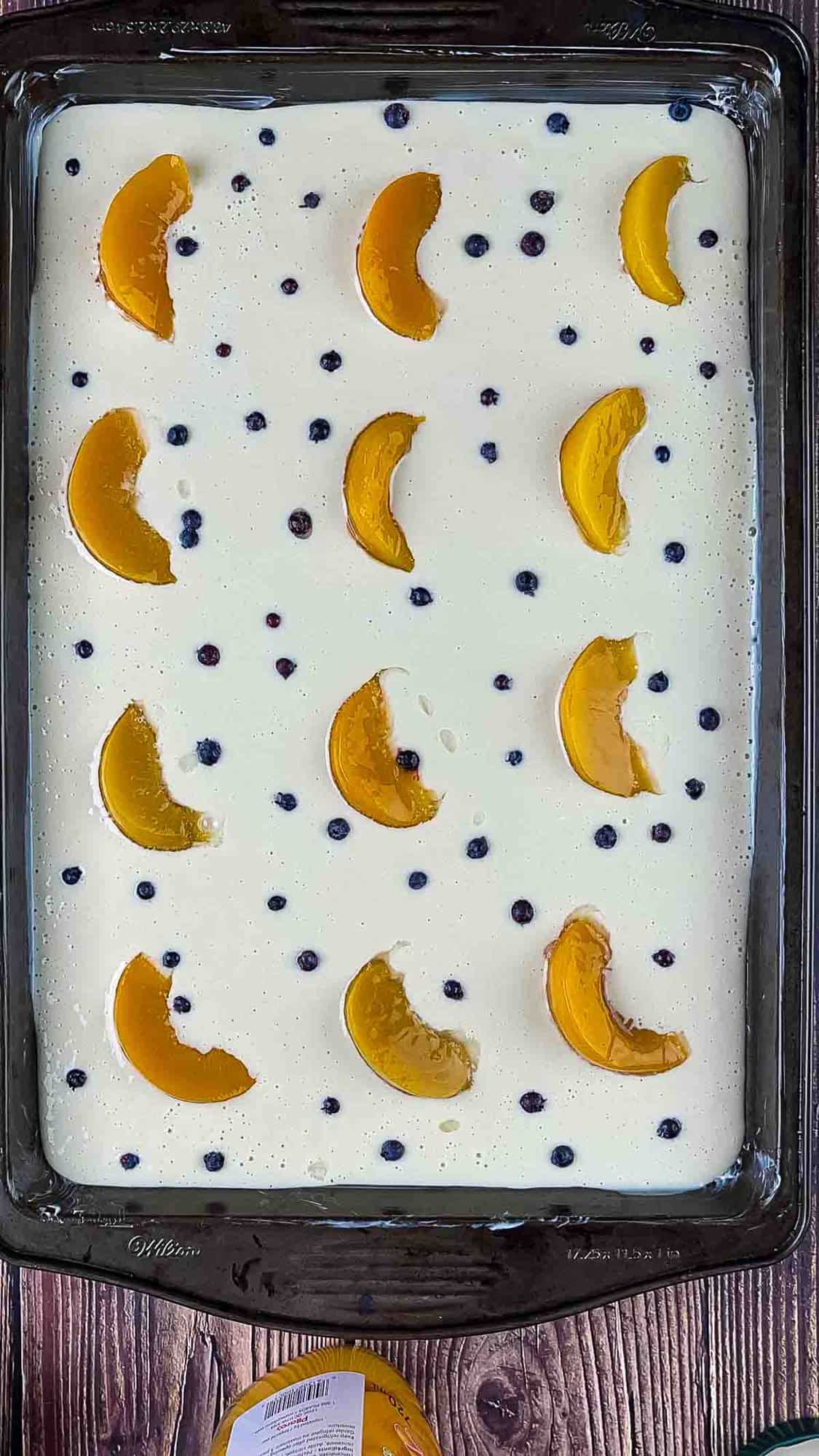 Sliced peaches and wild blueberries arranged on top of the pancake batter on the cookie sheet before baking.