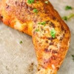 Smoked chicken quarters on a baking sheet, garnished with parsley, ready to be devoured.