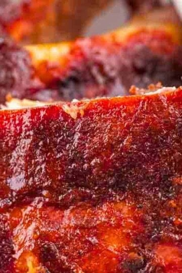 A plate of 321 smoked ribs with a rich glaze, garnished, served on a rustic wooden table.
