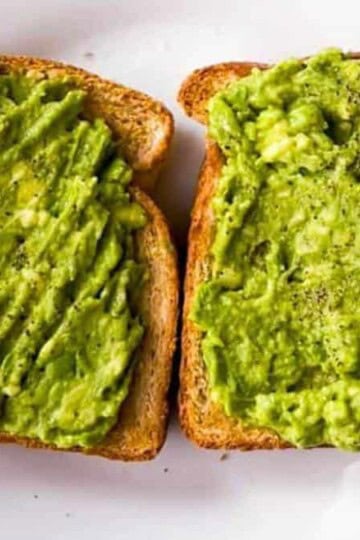Two slices of air fryer toast topped with mashed avocado.