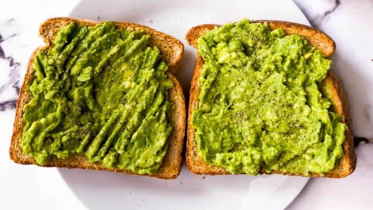 Two slices of air fryer toast topped with mashed avocado.