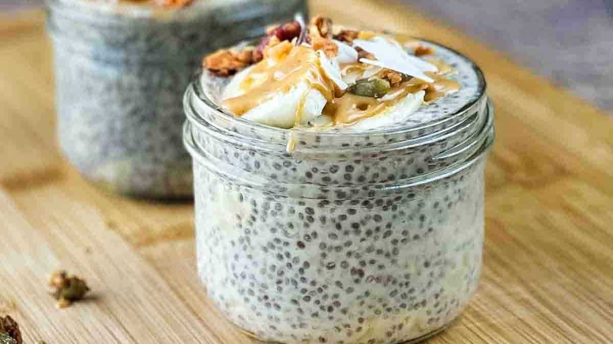 Two jars of banana chia pudding topped with sliced bananas and peanut butter.