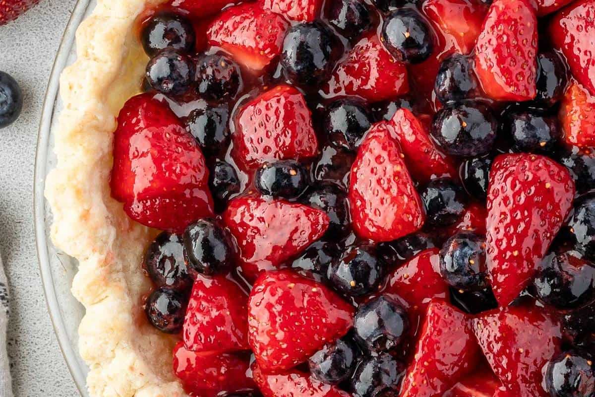 A whole Blueberry and Strawberry Pie on a serving plate, bursting with vibrant berries in a beautifully baked crust, capturing the essence of summer in a simple yet delicious dessert.