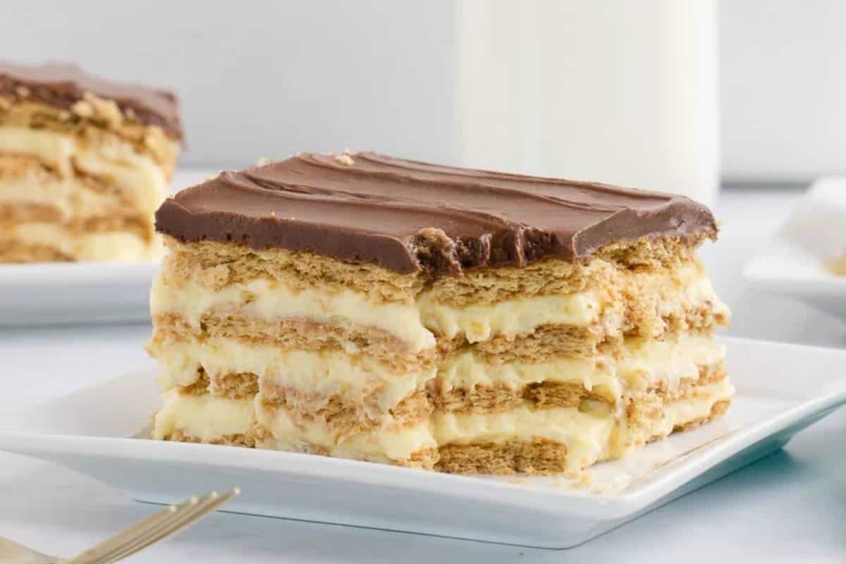 A slice of Chocolate Eclair Cake displayed on a plate, showcasing its luscious layers of graham crackers sandwiched between smooth, creamy filling and topped with a rich chocolate frosting.