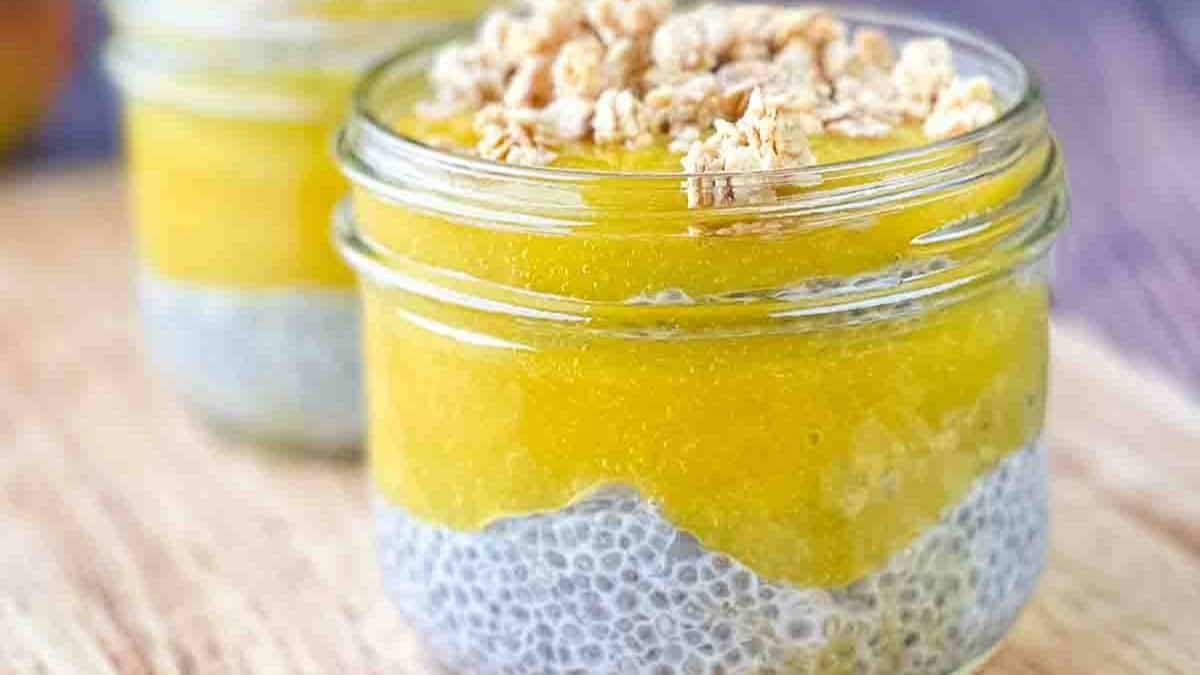 Two jars of coconut mango chia pudding topped with granola.