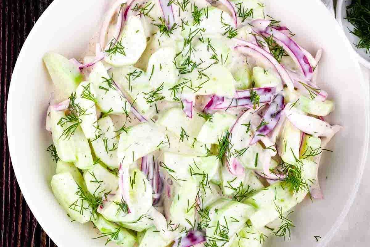 A bowl of Old-Fashioned Cucumber Salad featuring thinly sliced cucumbers and onions in a tangy vinegar dressing, ideal for family gatherings and summer picnics.