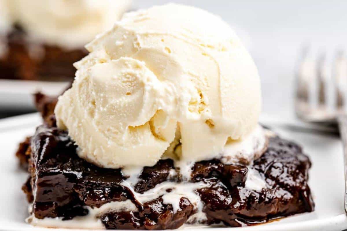 A serving of Hot Fudge Cake on a plate, with a molten chocolate sauce pooling around a moist, fudgy cake, topped with a scoop of vanilla ice cream.