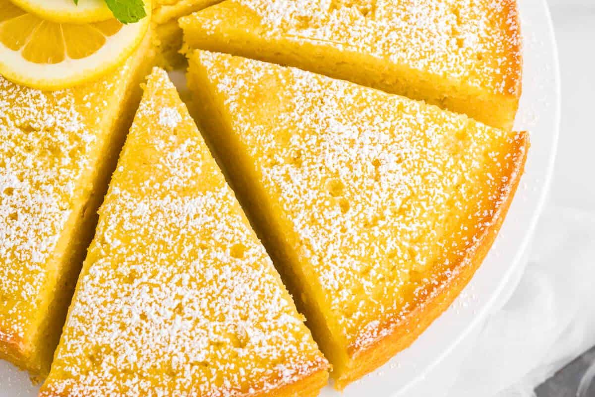 A light, airy slice of Lemon Ricotta Cake on a plate, showcasing its moist crumb and infused with a bright lemon flavor, topped with a dusting of powdered sugar for a simple, elegant dessert.