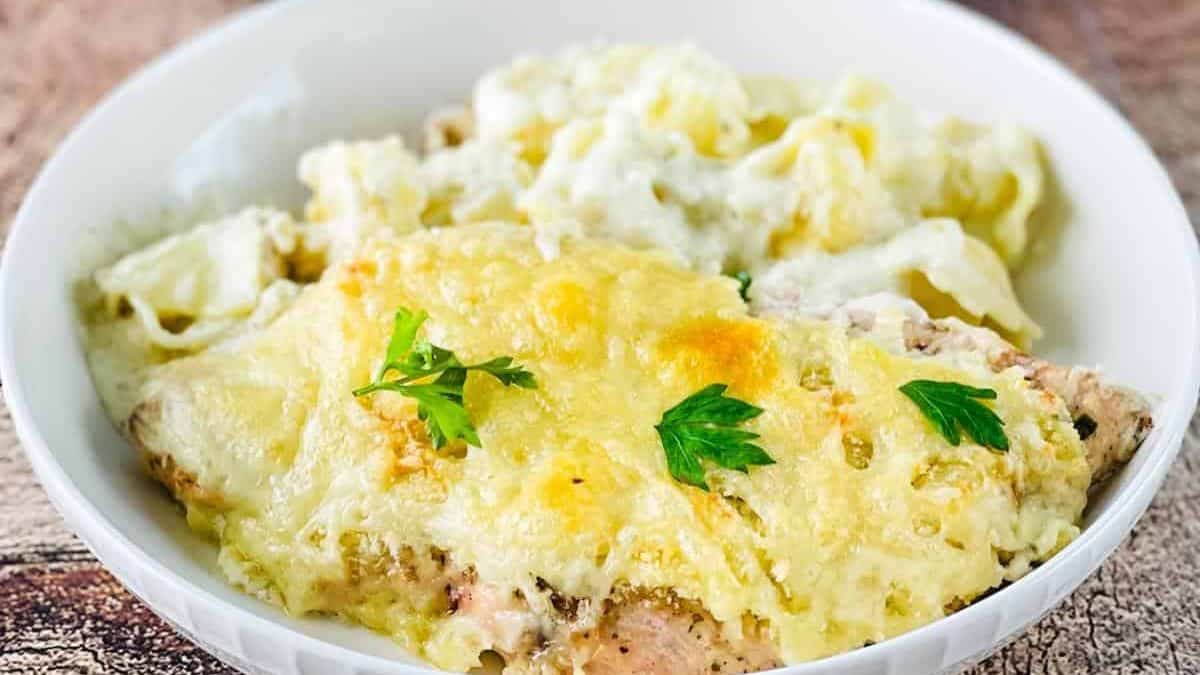 A plate of Asiago Tortelloni Alfredo with Grilled Chicken topped with creamy Alfredo sauce and garnished with fresh parsley.