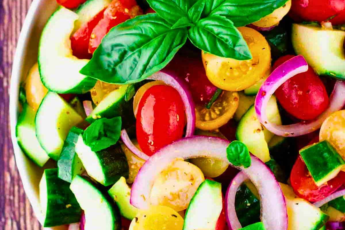 A bowl of Panera Bread's Tomato Basil Cucumber Salad copycat recipe, featuring juicy tomatoes, crunchy cucumbers, and fragrant basil, all tossed in a homemade Greek dressing.