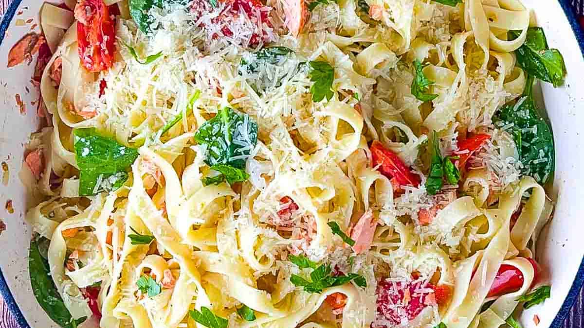 A plate of salmon pasta tossed in a light lemon garlic sauce and garnished with fresh parsley and lemon zest.