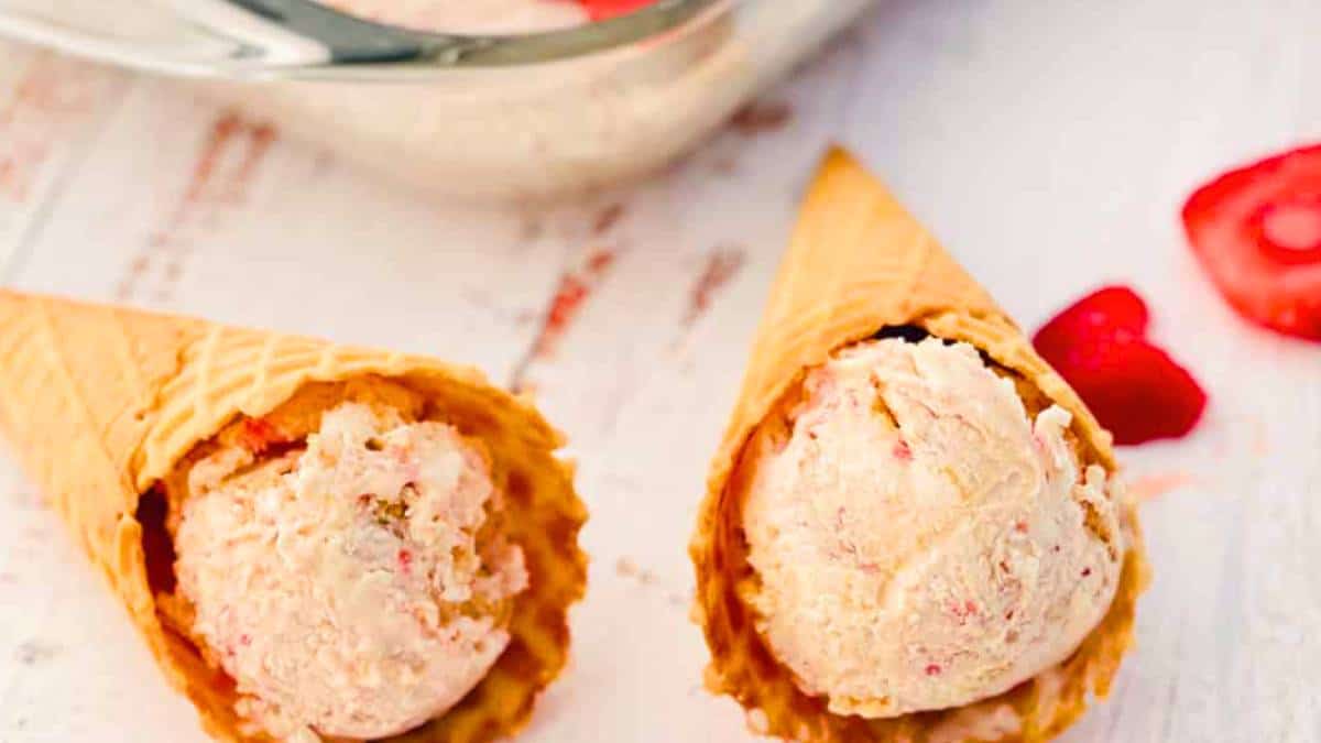 No-Churn Strawberry Cheesecake Ice Cream with swirls of strawberry and cheesecake flavor in a waffle cone.