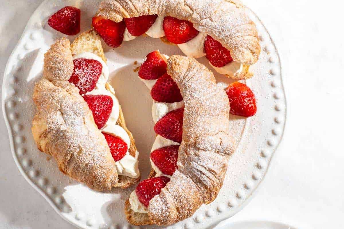 Strawberry croissants with Mascarpone cram arranged on a white plate.