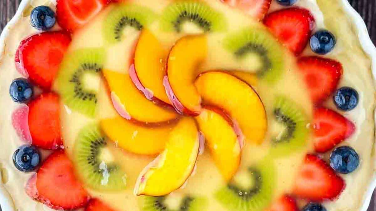 Sugar Cookie Fruit Pizza with a large cookie base, cream cheese icing, fresh fruits, and a sweet glaze.