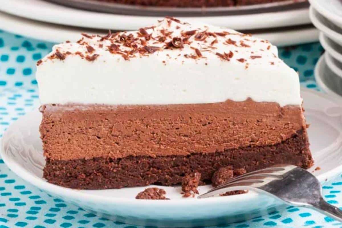 A slice of Triple Chocolate Mousse Cake on a plate, showcasing its three distinct layers of chocolate mousse, each more tempting than the last.