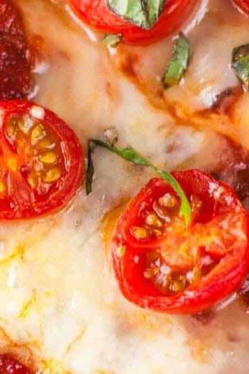 Air Fryer Naan Bread Pizza topped with fresh vegetables and melted cheese, served on a wooden board.