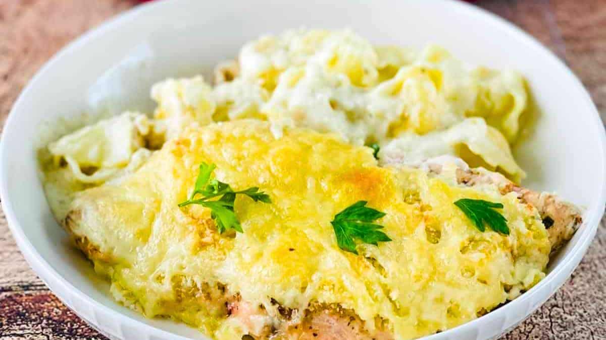 A plate of Asiago Tortelloni Alfredo with Grilled Chicken, garnished with fresh herbs.