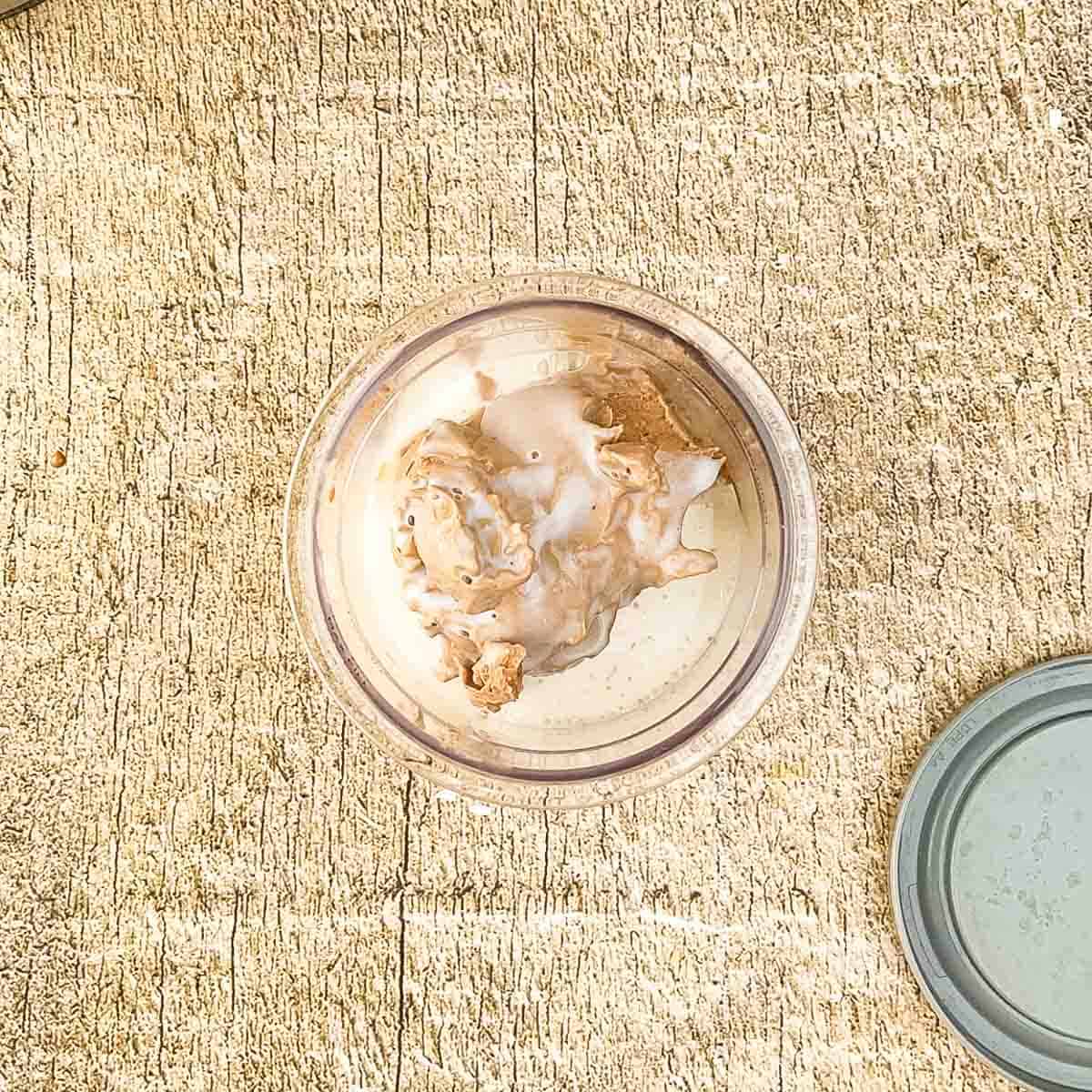 Chocolate ice cream and milk in a Ninja Creami pint jar.
