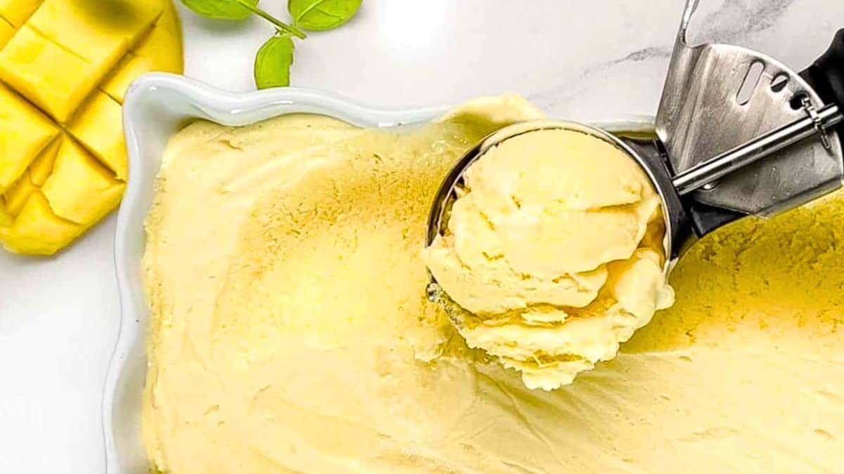 The frozen mango ice cream scooped up into an ice cream scoop that is placed on top of the loaf pan.