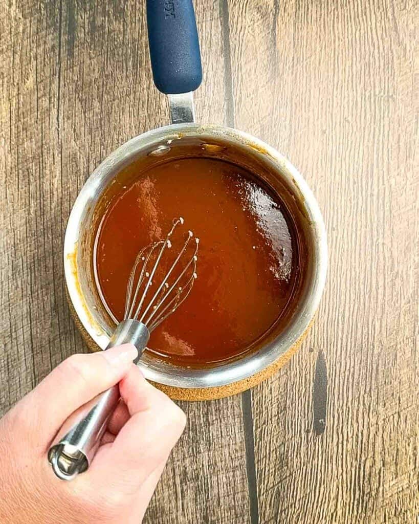 Mixing BBQ sauce, maple syrup, butter, and hot sauce in a saucepan on low heat until smooth.