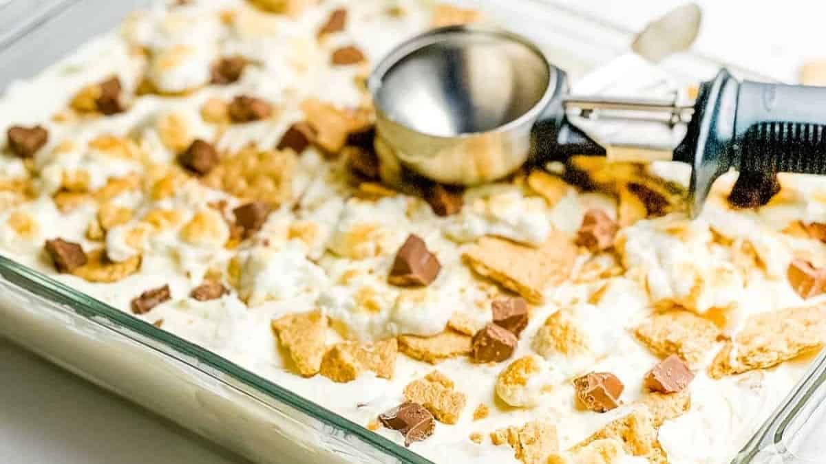 No churn smores ice cream in a baking dish, garnished with graham crackers, toasted marshmallows, and chocolate chunks.