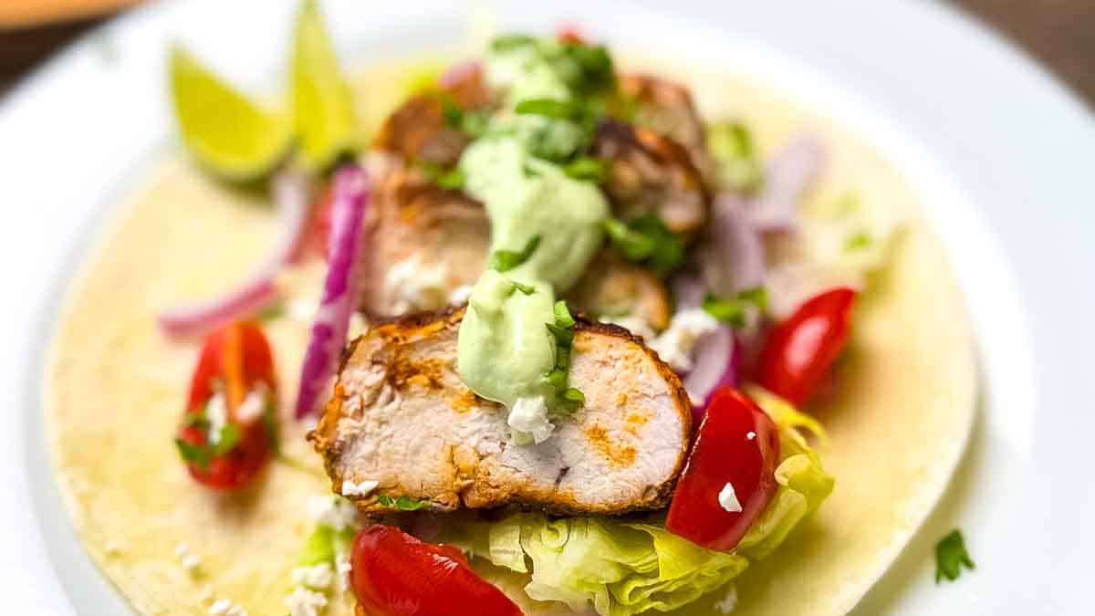 A blackened chicken taco topped with avocado lime crema.