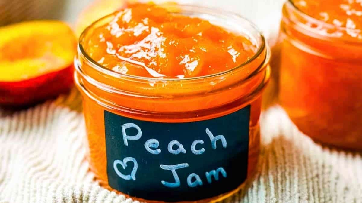 A small jar of fresh homemade peach jam with a label, ready to be served.