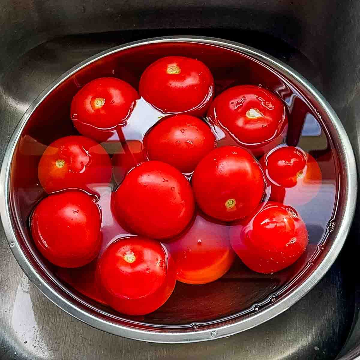 Whole tomatoes in a bowl of water to get washed.