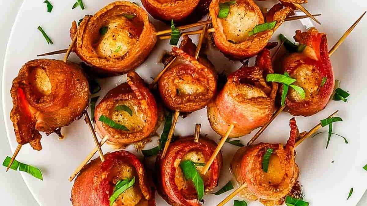 Golden brown bacon-wrapped scallops arranged on a serving platter.