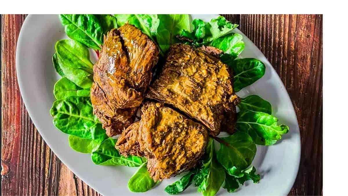 A tender venison roast on a bed of lettuce, ready to be sliced or shredded.
