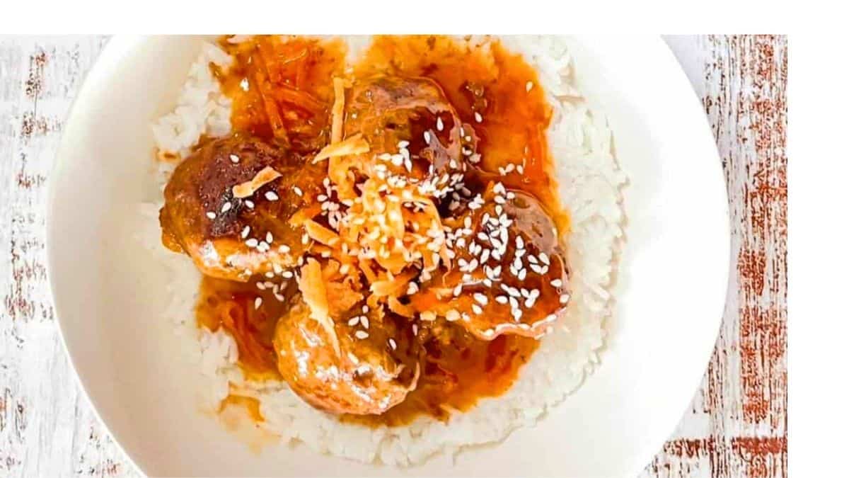 Glossy sweet and sour meatballs garnished with sesame seeds.