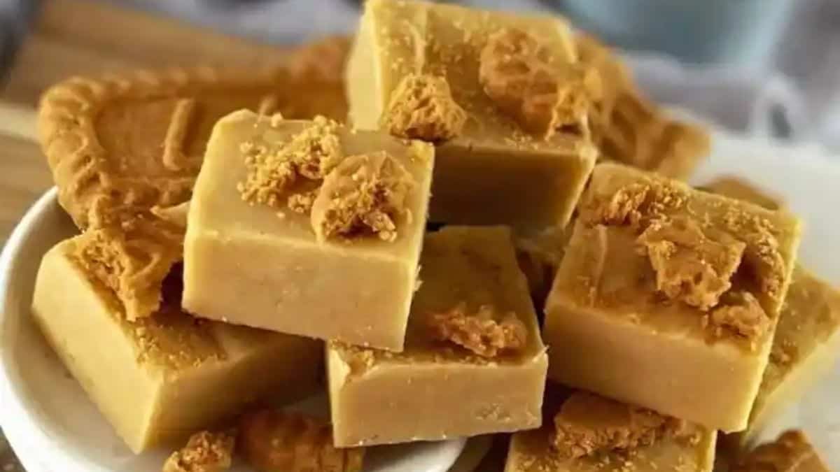 Squares of golden-brown fudge with visible swirls of Biscoff cookie butter throughout, topped with crushed speculoos cookies.