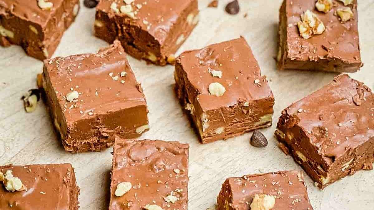 Dark chocolate fudge squares studded with chopped walnuts, cut into perfect squares with a glossy sheen and slightly crumbly edges.
