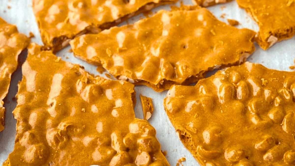 Golden-amber pieces of soft peanut brittle filled with whole peanuts, showing a slightly bendy texture rather than a hard shine.