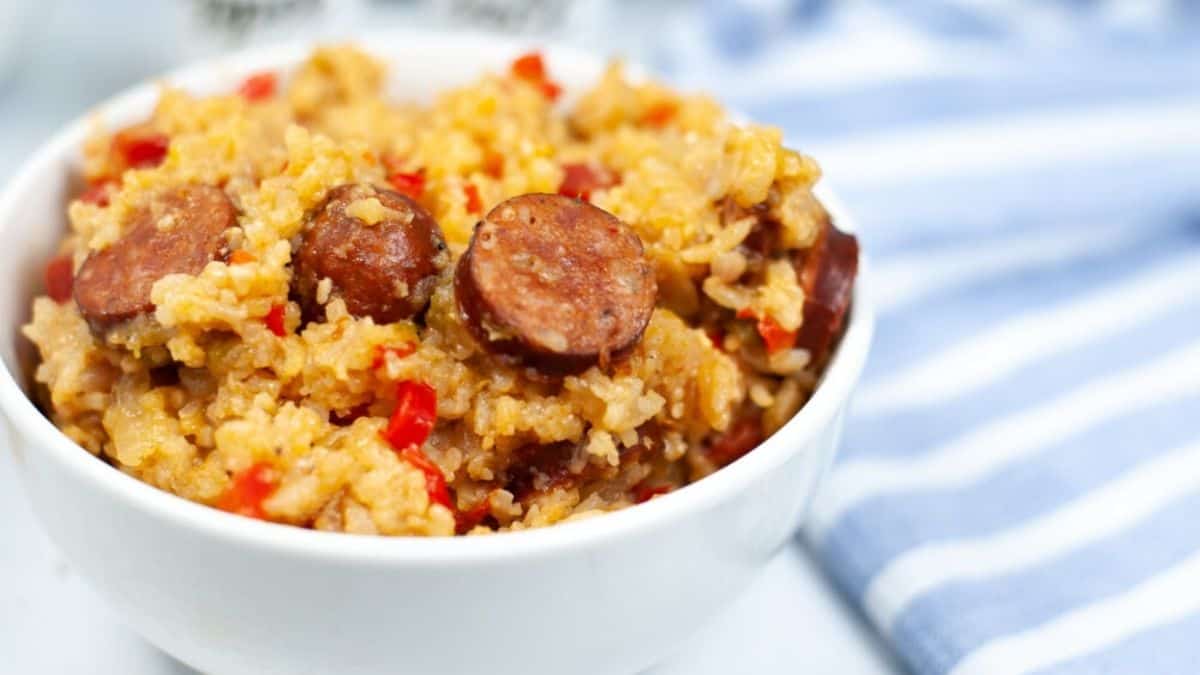 A serving bowl filled with traditional jambalaya showing plump shrimp, chunks of sausage, and tender chicken nestled among red-tinged rice.