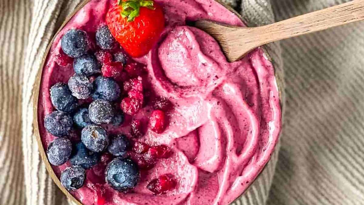 A magenta smoothie bowl topped with fresh berries.