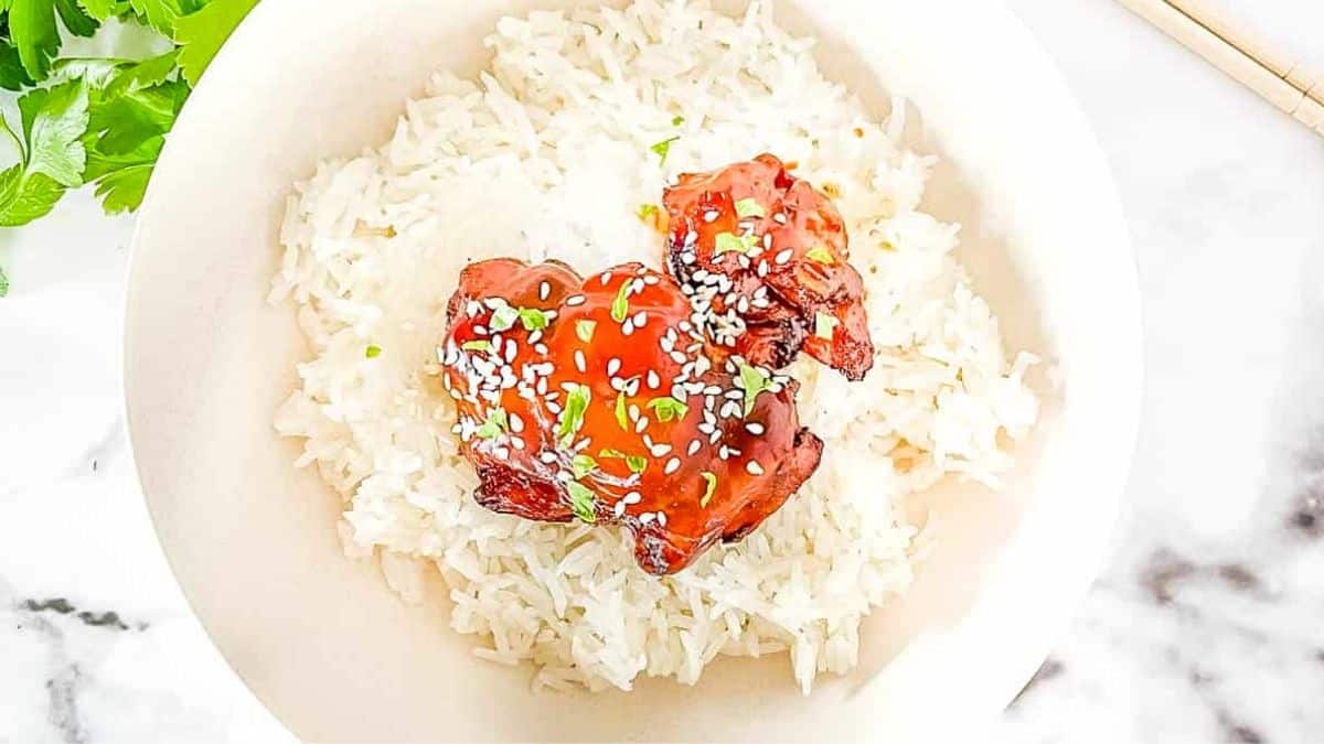 Air fried teriyaki chicken thighs on white rice, garnished with sesame seeds.