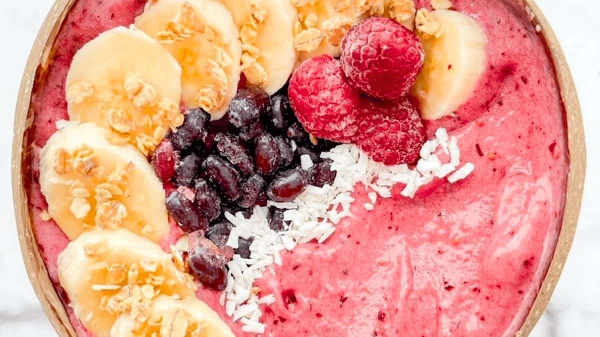 A deep purple bowl loaded with mixed berries and granola.