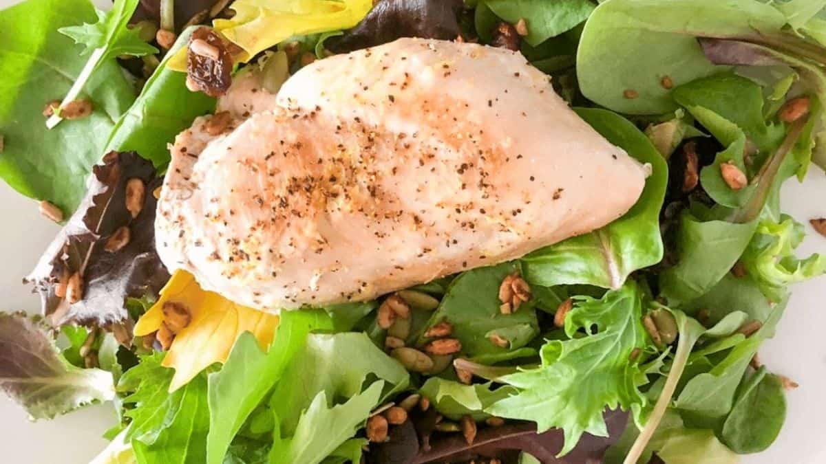Juicy chicken breast placed on a green salad.