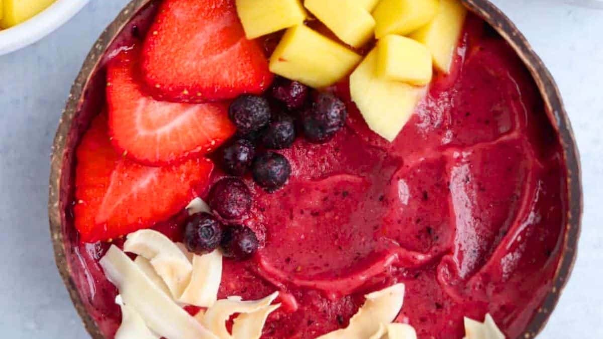 A vibrant berry smoothie bowl topped with fresh fruit.