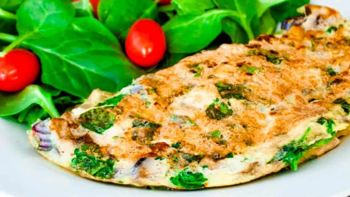 Spinach omelet on a white plate with a spinach salad.