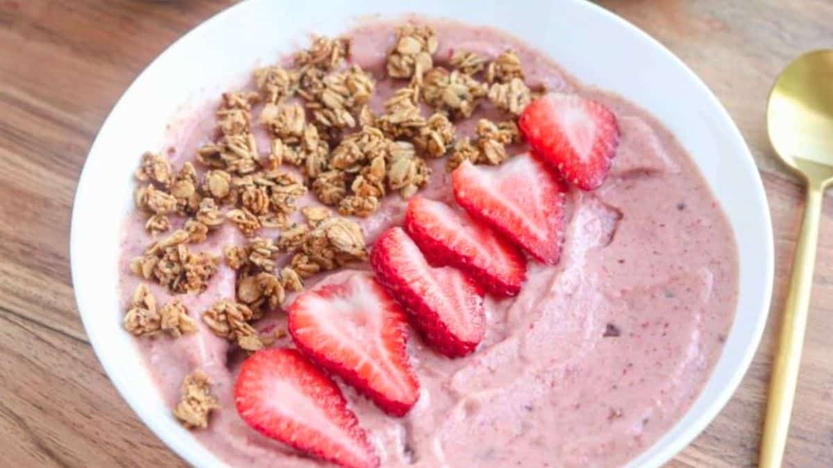 A pink smoothie bowl topped with granola.