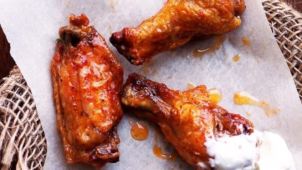 Crispy buffalo wings arranged on a table with blue cheese sauce.